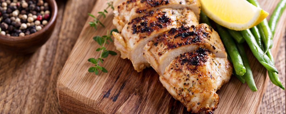 Grilled chicken on a cutting board with thyme and green beans