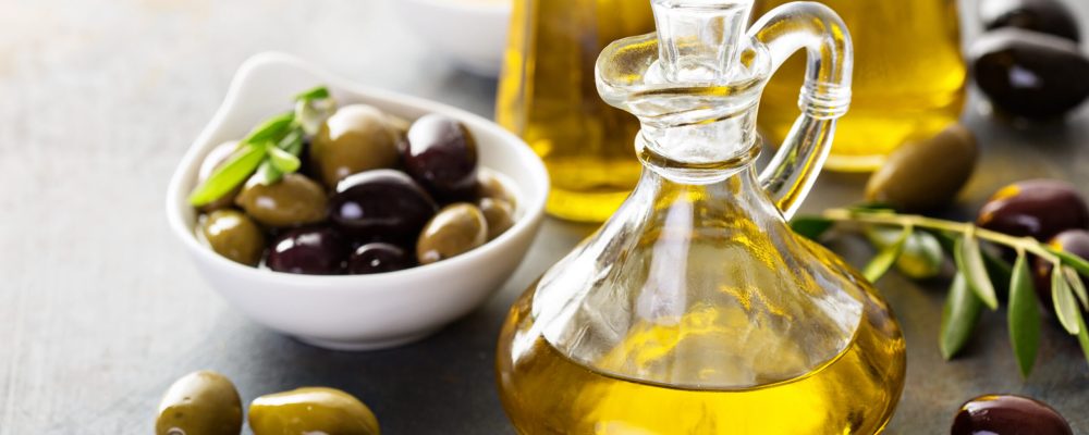 Olive oil in vintage bottles with black and green olives and leaves copyspace on rustic background