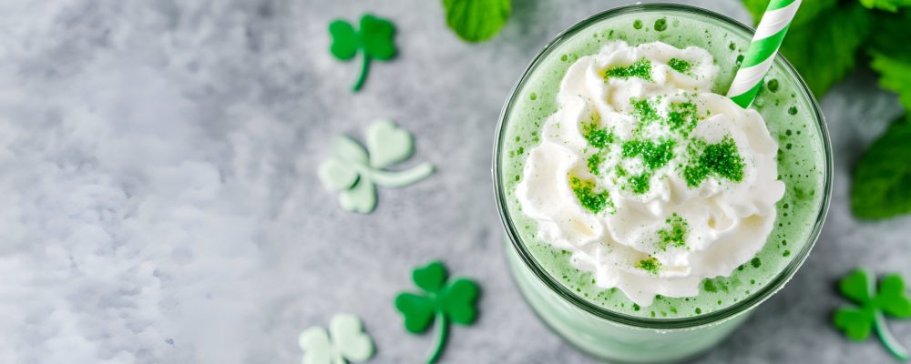 Festive St. Patrick's Day green milkshake with whipped cream and shamrocks. Perfect for holiday celebrations.