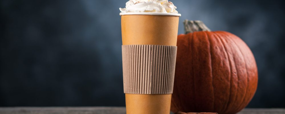 Pumpkin spice latte in a paper cup on dark background