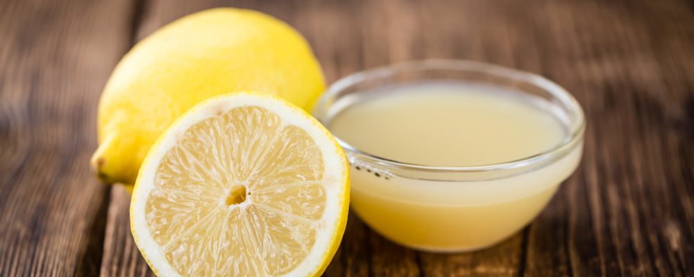 Homemade Lemon Juice on an wooden table (selective focus) as detailed close-up shot