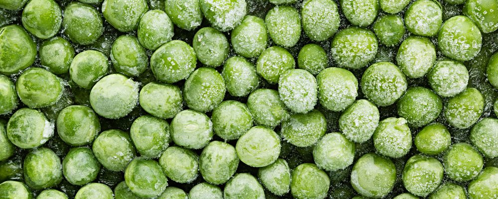 Fresh frozen green peas with hoarfrost closeup as background. Healthy vitamin food.