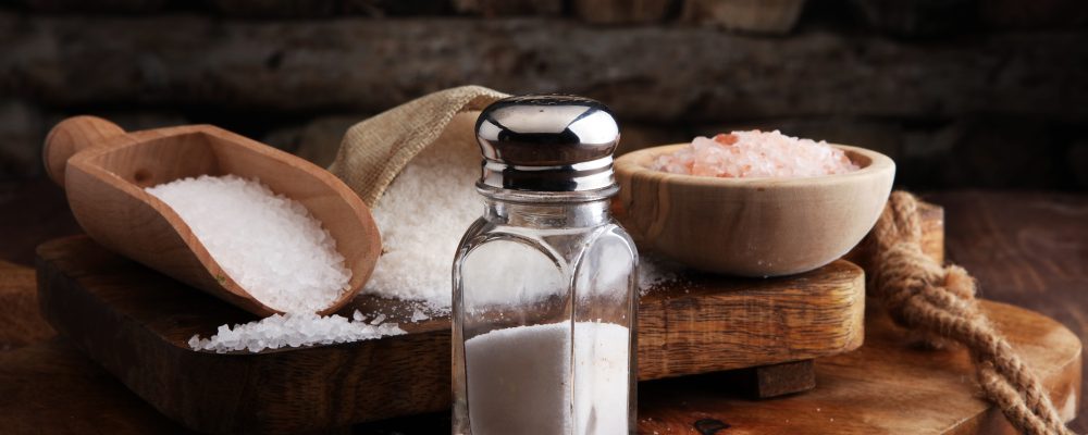 Salt Shaker and salt on wooden table.