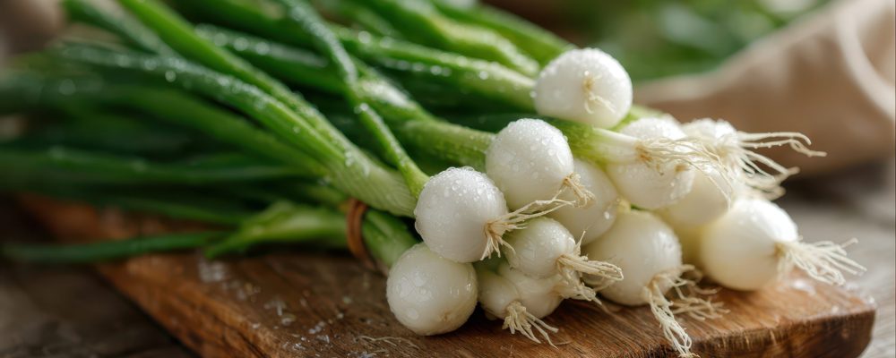 Crisp white bulbs and green tops of fresh scallions arranged on a kitchen board