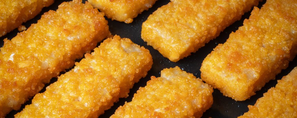Crispy fish sticks frying in a pan close-up