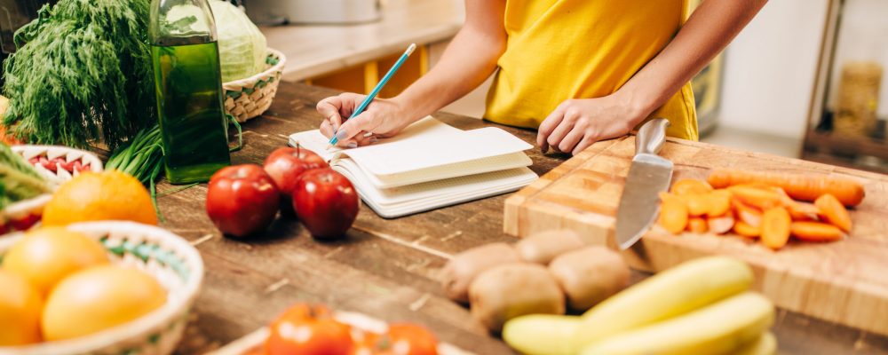 Female person cooking on the kitchen, healthy bio food. Vegetarian diet, fresh vegetables and fruits on wooden table