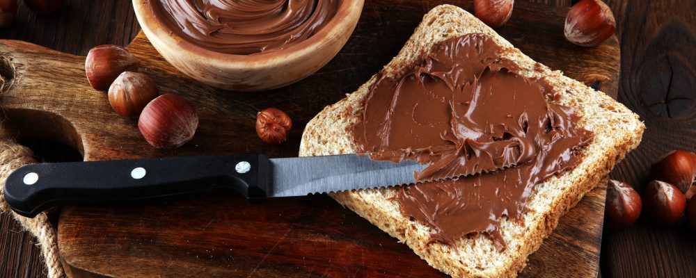 Homemade hazelnut spread with toast and in wooden bowl for breakfast. Hazelnut Nougat cream.