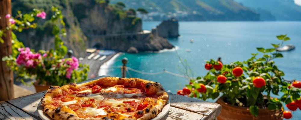 Traditional Italian pizza served with a glass of white wine on a seaside terrace overlooking a dramatic coastal landscape. Scenic travel dining scene with Mediterranean cuisine, blue water, and sunny vacation atmosphere.