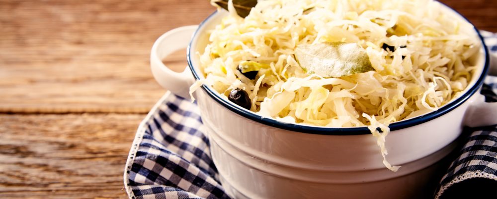 Bowl of sauerkraut cabbage on dishcloth against wooden table