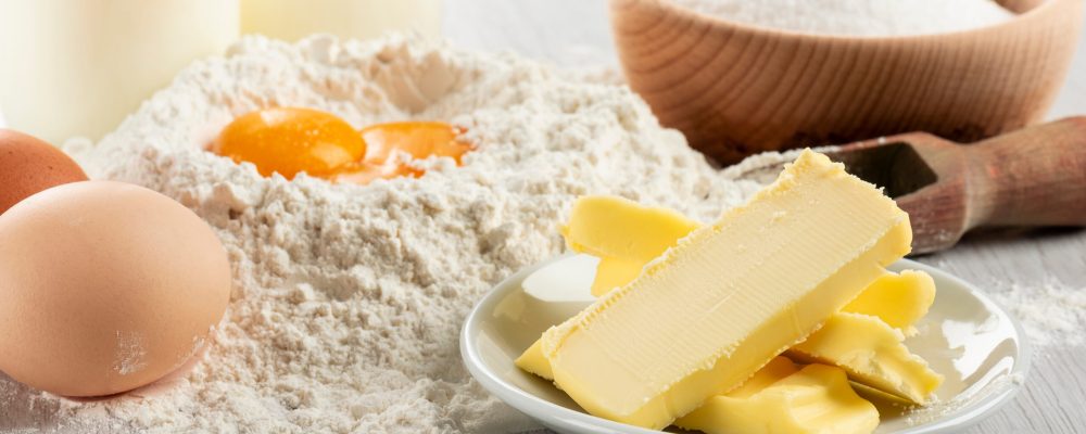 Ingredients for dough and pastry on wooden table, close up on butter.