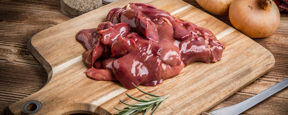 Raw chicken liver on cutting board. Selective focus.