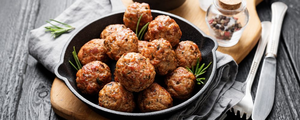Meatballs served with tomato sauce in frying pan .
