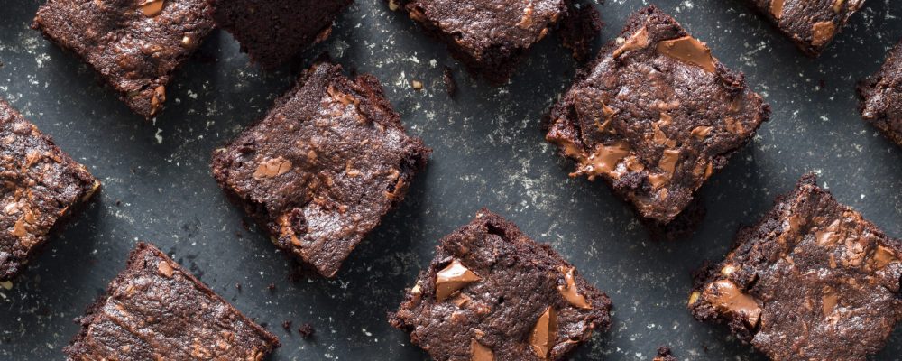 Chocolate brownie squares on black mottled background - baked chocolate brownie cakes