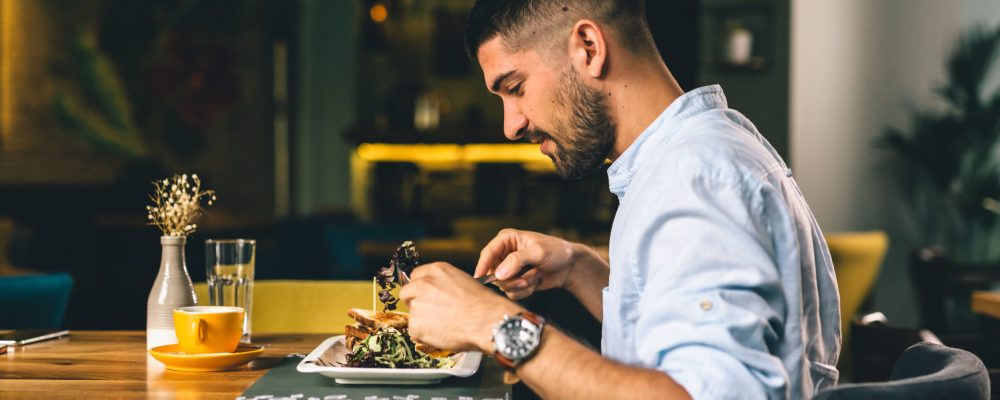 man having breakfast or dinner in cafe