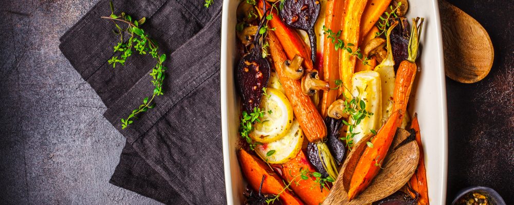 Baked carrots, sweet potatoes, beets and zucchini in oven dish, top view.