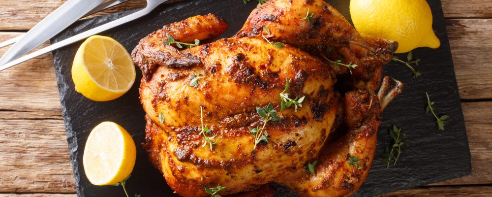 Homemade chicken rotisserie with thyme, lemon closeup on a slate
