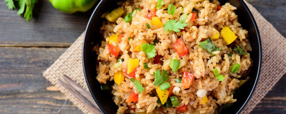Fried rice with vegetables in a black bowl, Asian food, top view