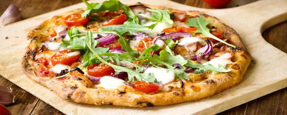 Freshly baked pizza with arugula, tomato, red onion and mozzarel