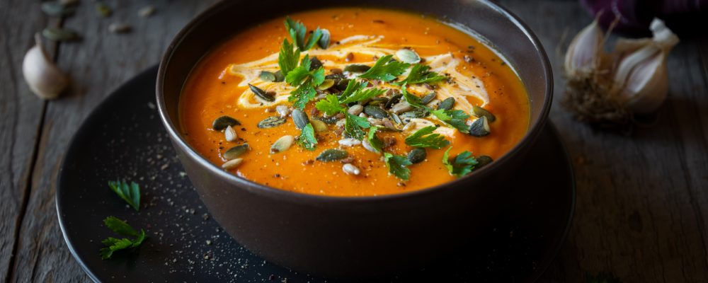 Pumpkin soup with cream, parsley and pumpkin seeds on dark
