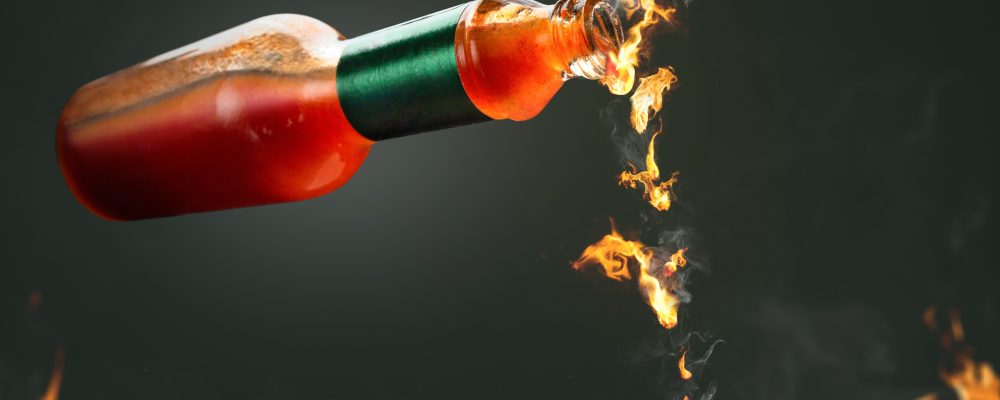 Burning hot chili sauce dripping from a bottle