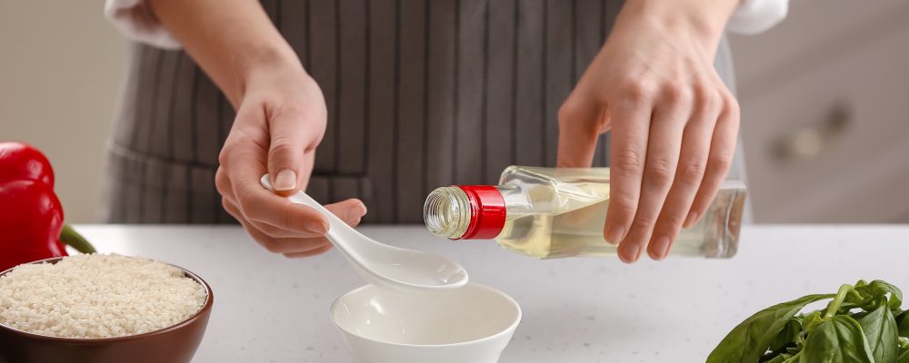 Woman preparing sauce with rice vinegar in kitchen