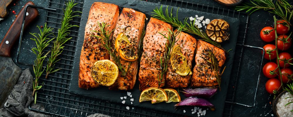 Salmon. Pieces of grilled fish on a black stone background. Recipe. Seafood. Free space for text.