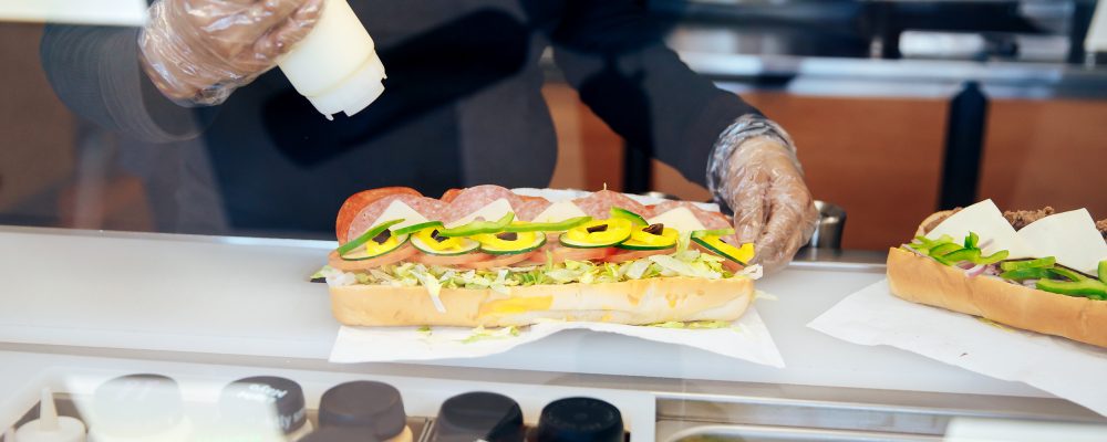 pouring dressing on a sub in the restaurant. the kitchen of fast food restaurant