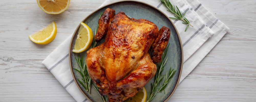 Homemade Lemon and Herb Rotisserie Chicken on a Plate, top view. Flat lay, overhead, from above.