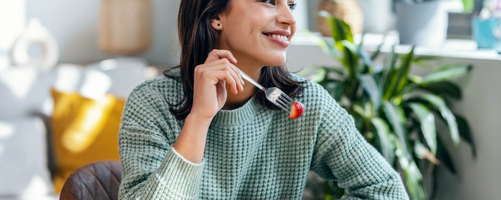 Portrait of beautiful smiling woman eating healthy salad at home.