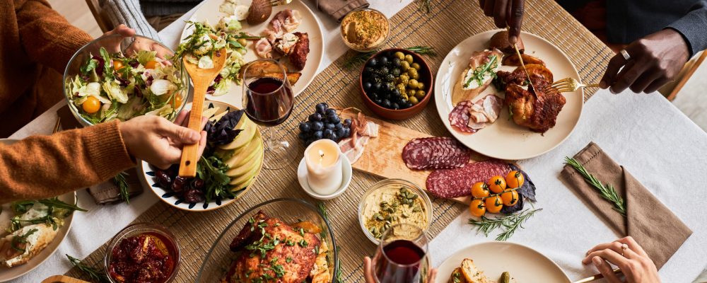 High angle view at diverse group of friends enjoying homemade food at festive dinner table with roasted turkey or chicken, copy space