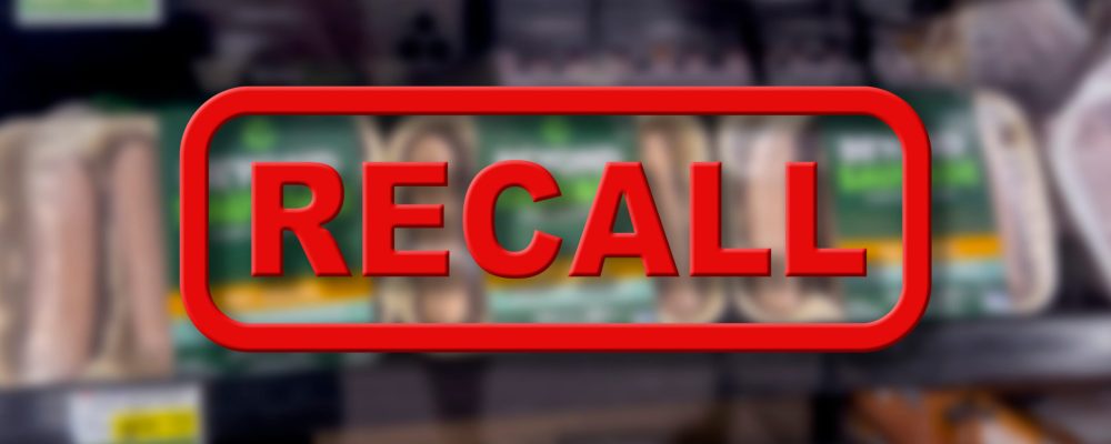 Blurred background of vegetarian meat products for sale with the red text Recall in the foreground