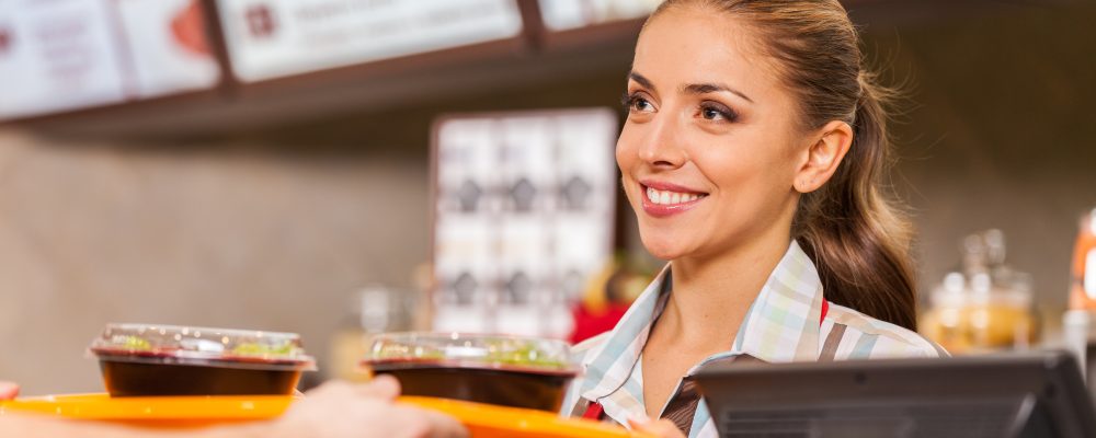 Restaurant worker serving two fast food meals with smile. woman holding tray with salads at fast food restaurant