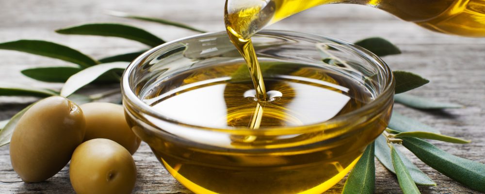 Bottle pouring virgin olive oil in a bowl close up