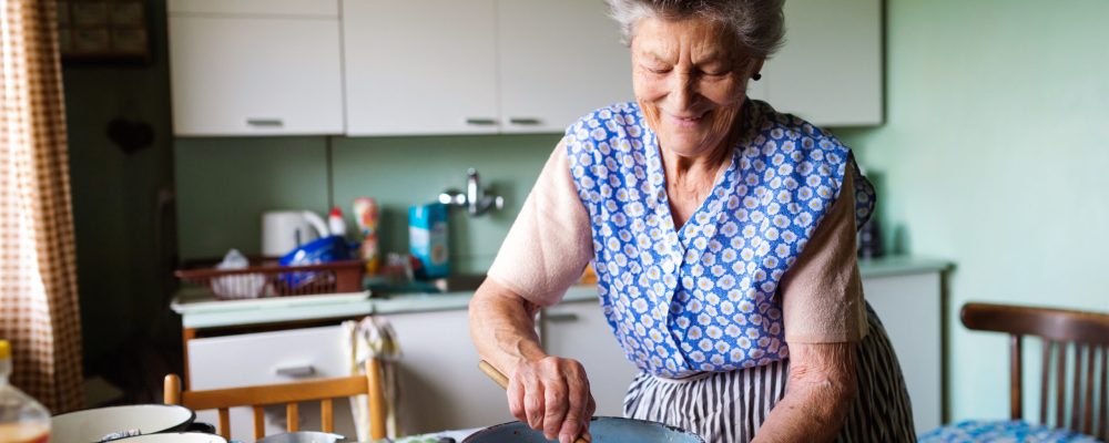 Senior woman baking pies in her home kitchen.  Mixing ingredients.